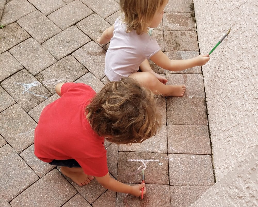 boy tracing letter written in chalk on driway