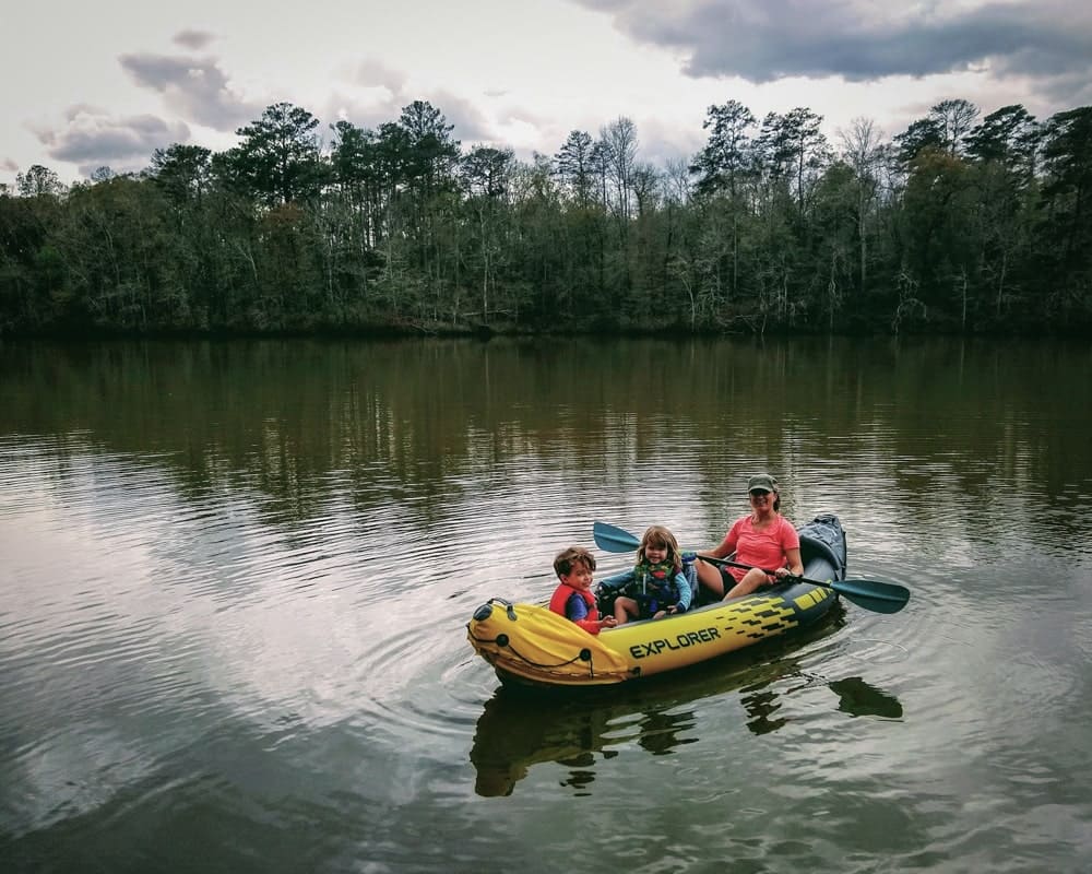 woman, girl, and boy on a yellow inflatable kayak on lake