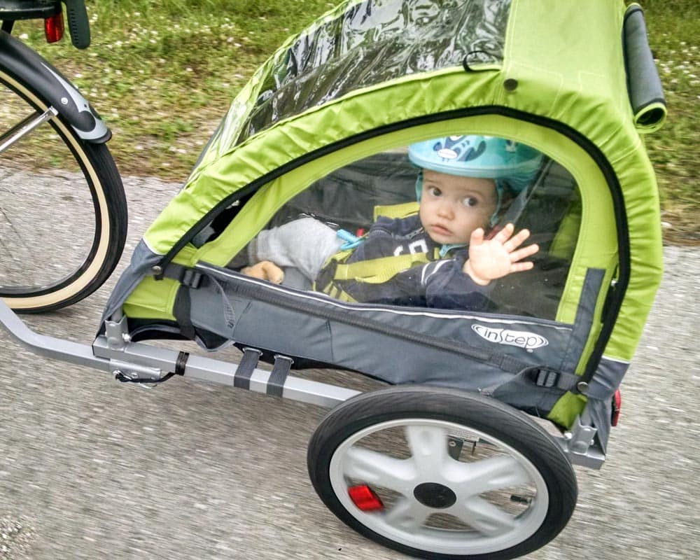 toddler in green bike trailer