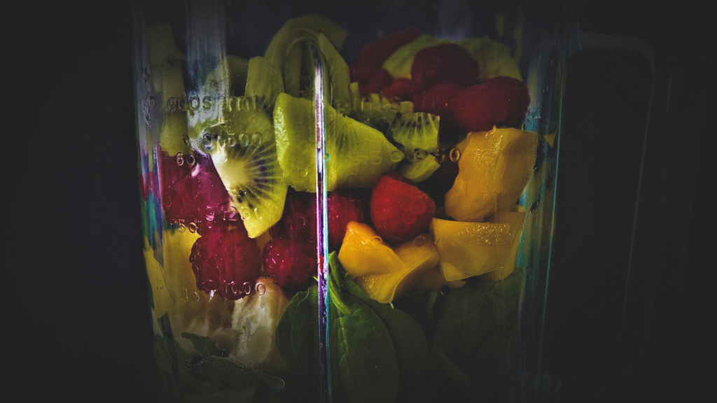 close up of a variety of fruits in a blender