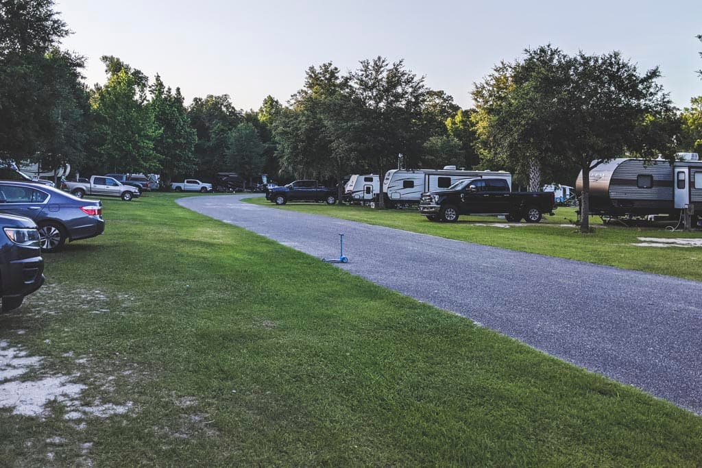 Campers, trucks, and RVs parked on either side of a paved road in campground at Hart Springs Park.