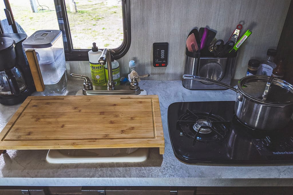 cutting board over sink and pot over stove in RV kitchen