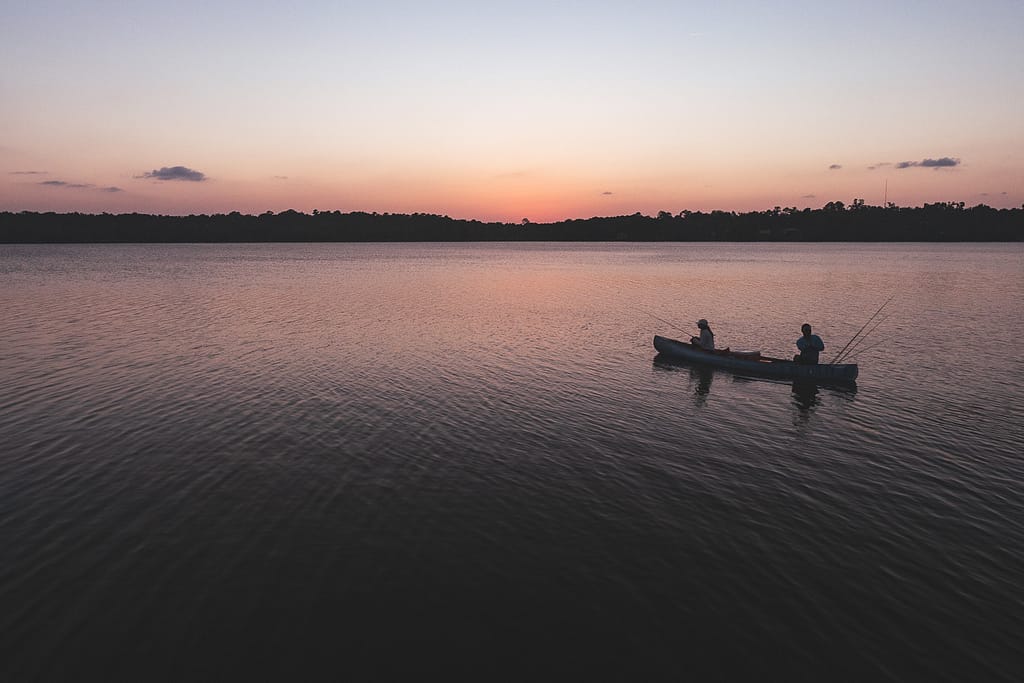 Two man fishing on canoe on Lake Wauberg under sunset skies at Payne's Prairie Preserve State Park