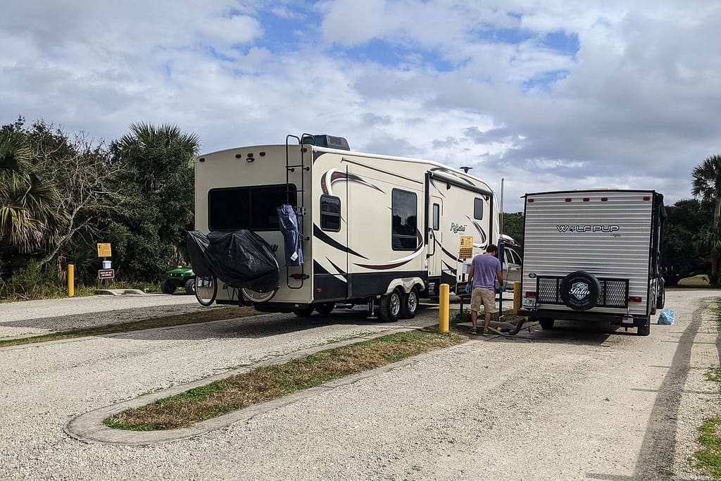 A fifth wheel and a travel trailer next to each other at the dump station in Anastasia State Park