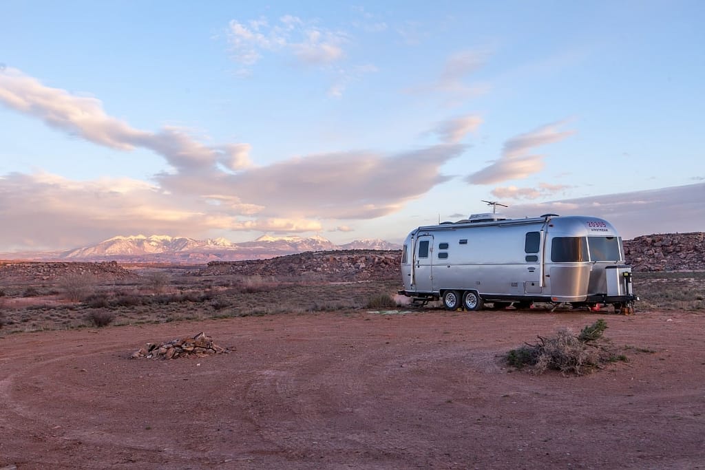 Airstream travel trailer in an open desert field under blue sky