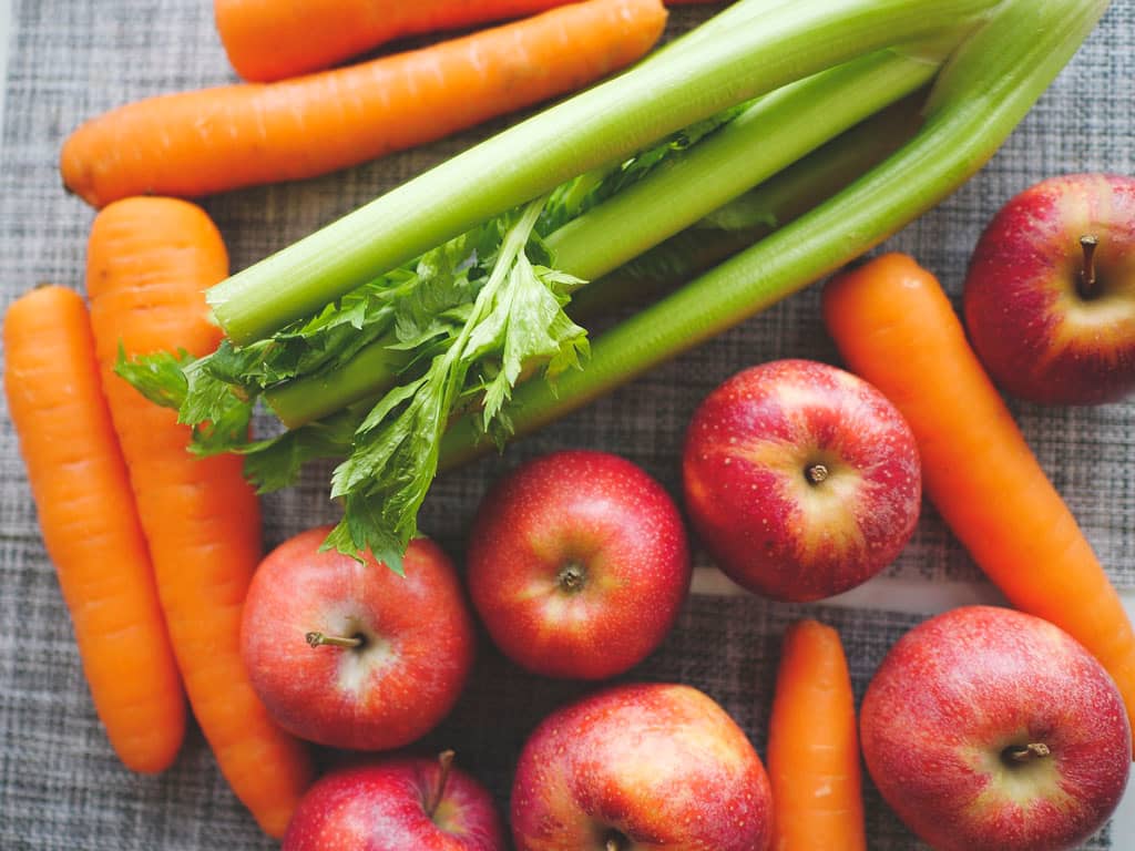 flat lay of carrots, celery and red apples