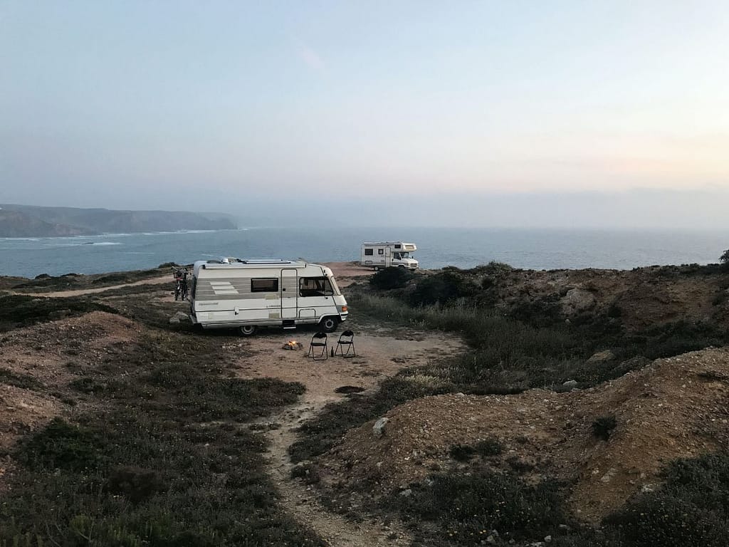 Two white RVs dry camping by a cliff near the ocean