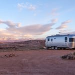 Airstream travel trailer in an open desert field under blue sky