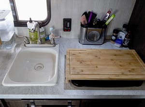 camper sink with cutting board over stove