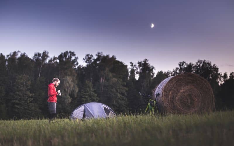 Man standing next to tent in open field at night